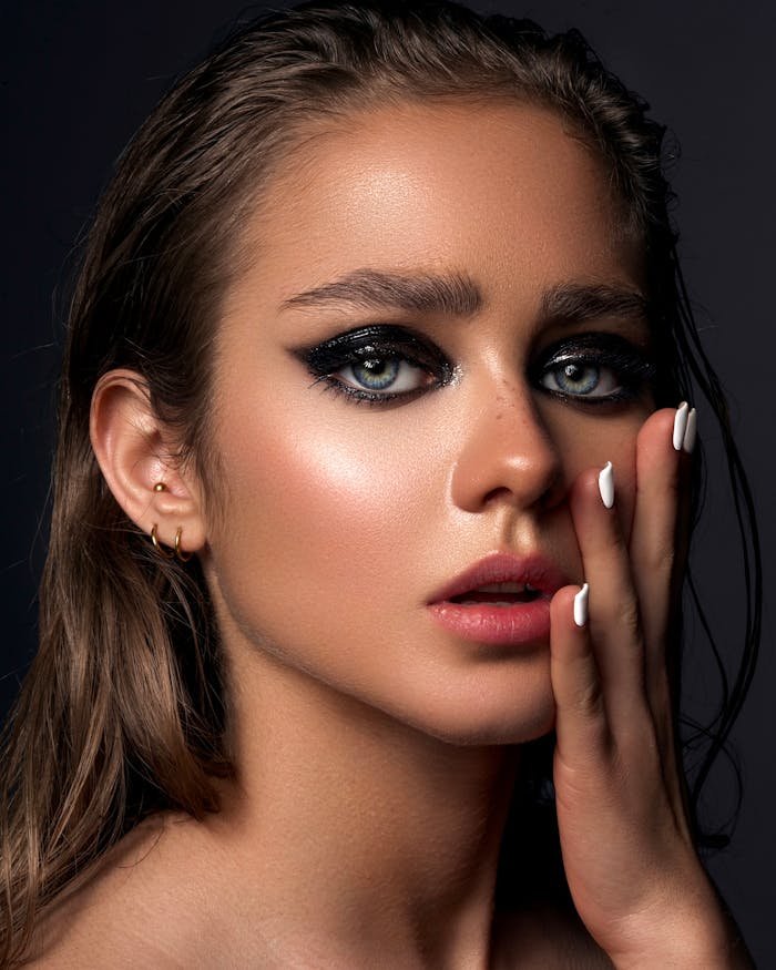 Stunning portrait showcasing a young woman with dramatic makeup, blue eyes, and elegant styling.